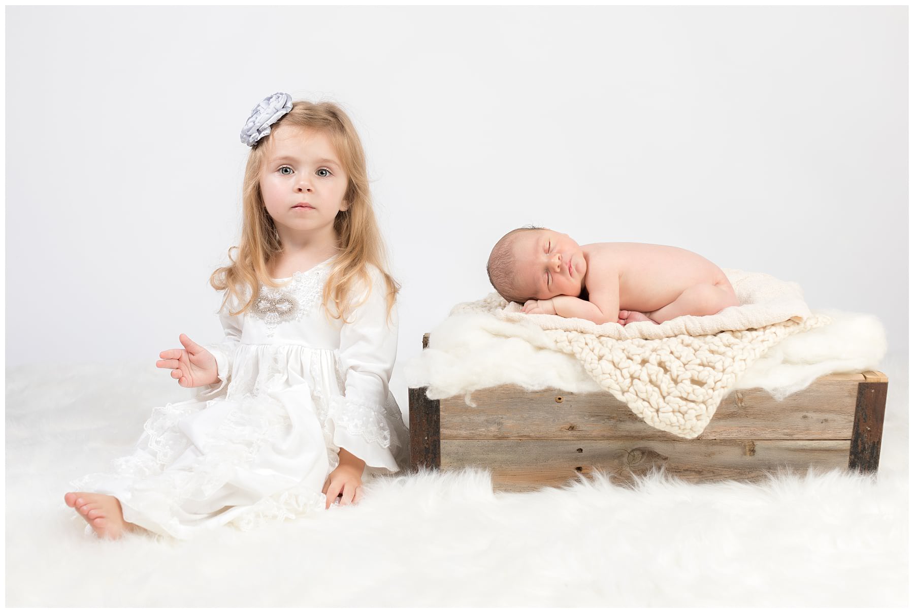 Newborn on white blankets with big sister