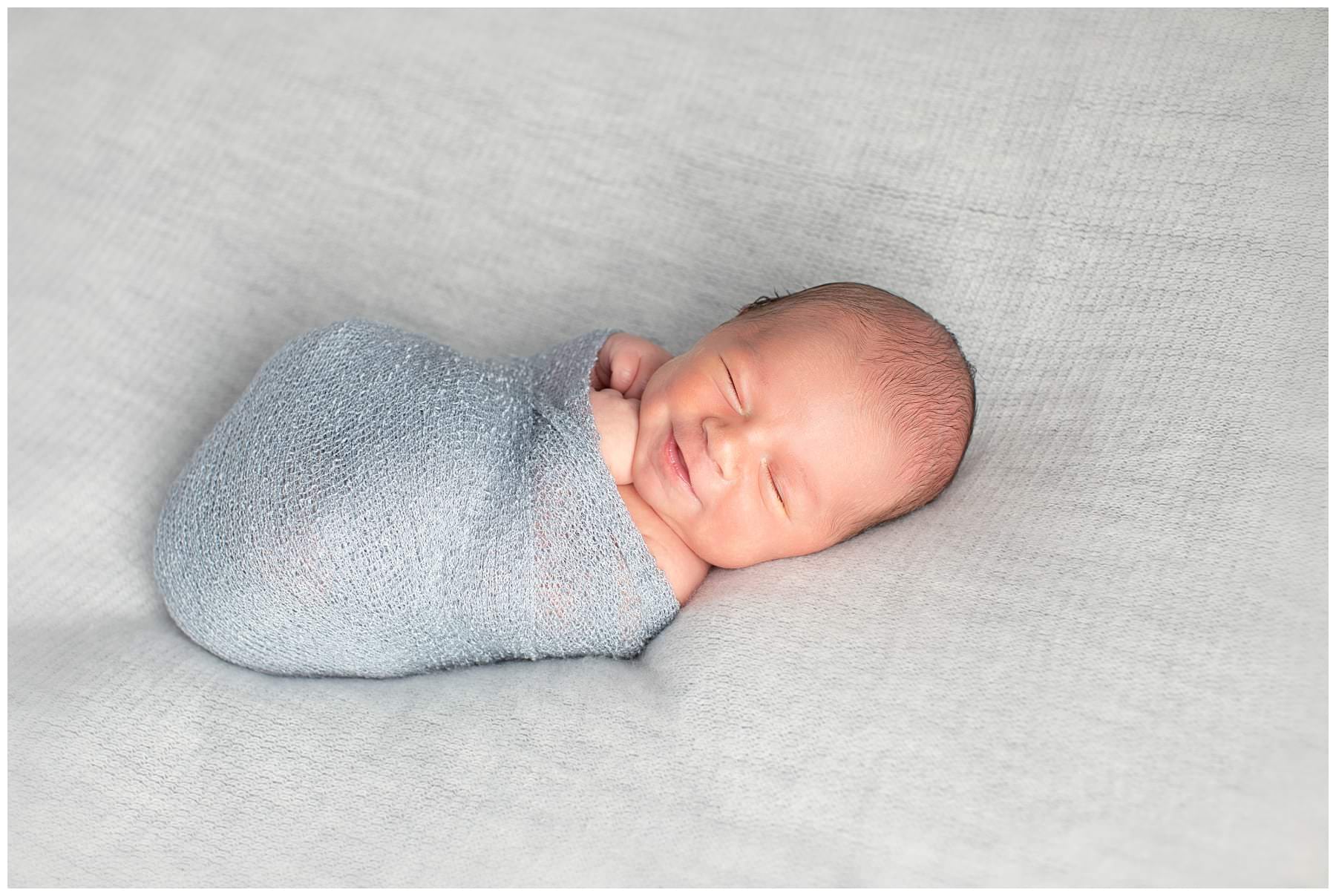 Newborn portrait smiling in grey wrap in Berks County PA studio